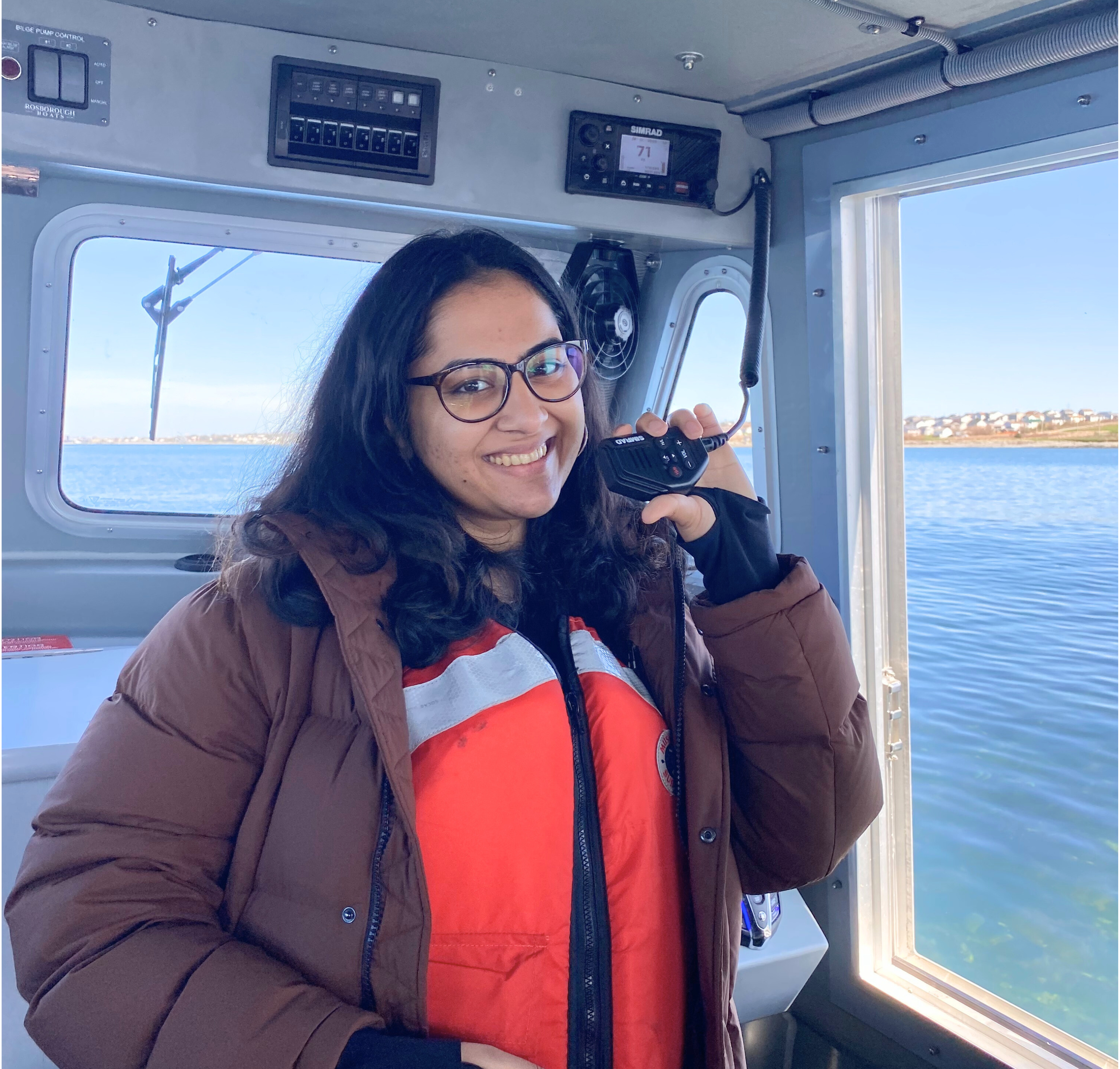 Aprajita smiles with holding up a radio aboard the SEATAC vessel.